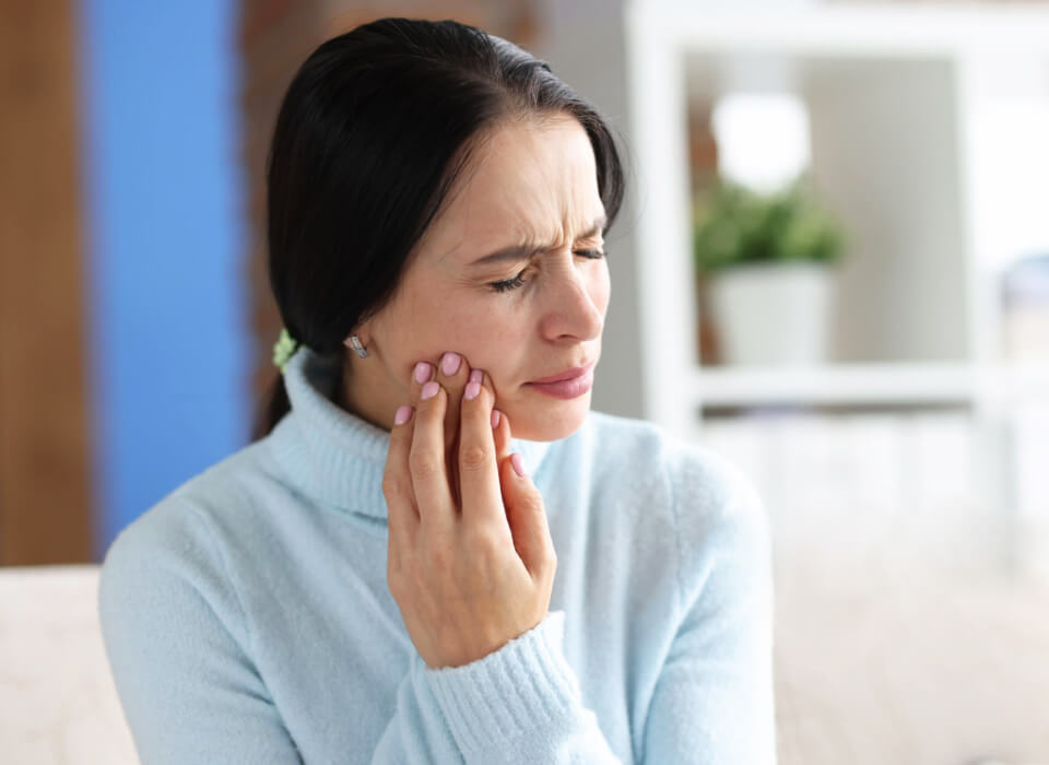 A woman feeling tooth pain by holding her cheek
