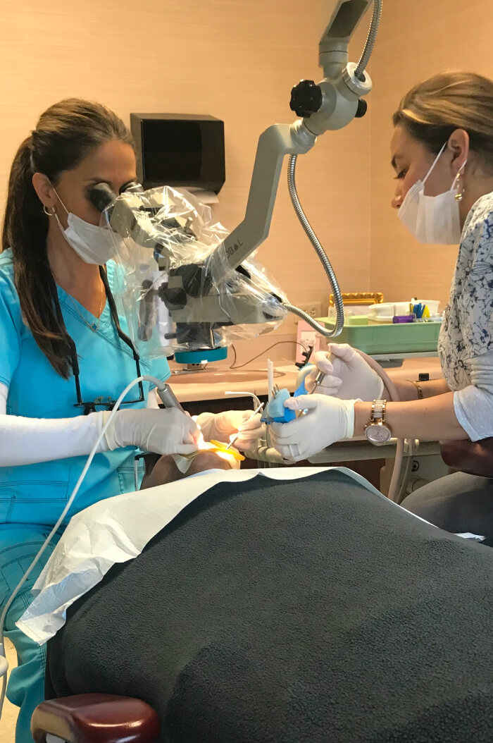 A lady dental doctor and her assitant working with a patient