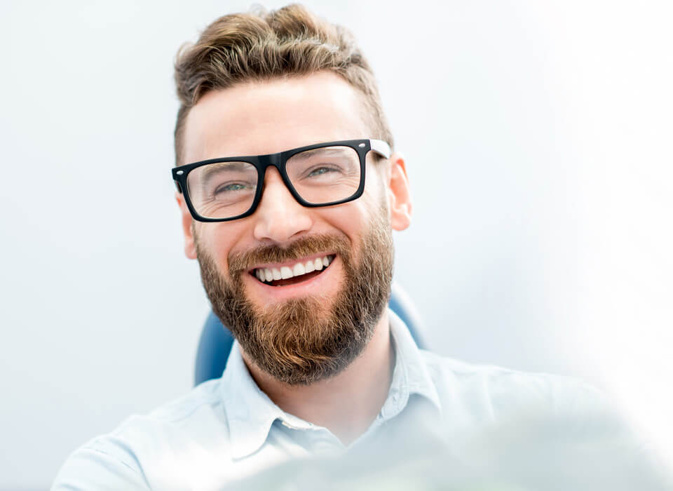 Stock image of a smiling person with beard and eye glasses
